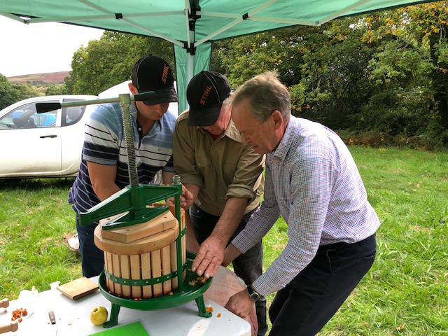 Three men pressing apples 